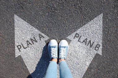 A planı ile B planı arasında seçim yapmak. Okların yanındaki kadın yolun üstünde, manzaranın üstünde.