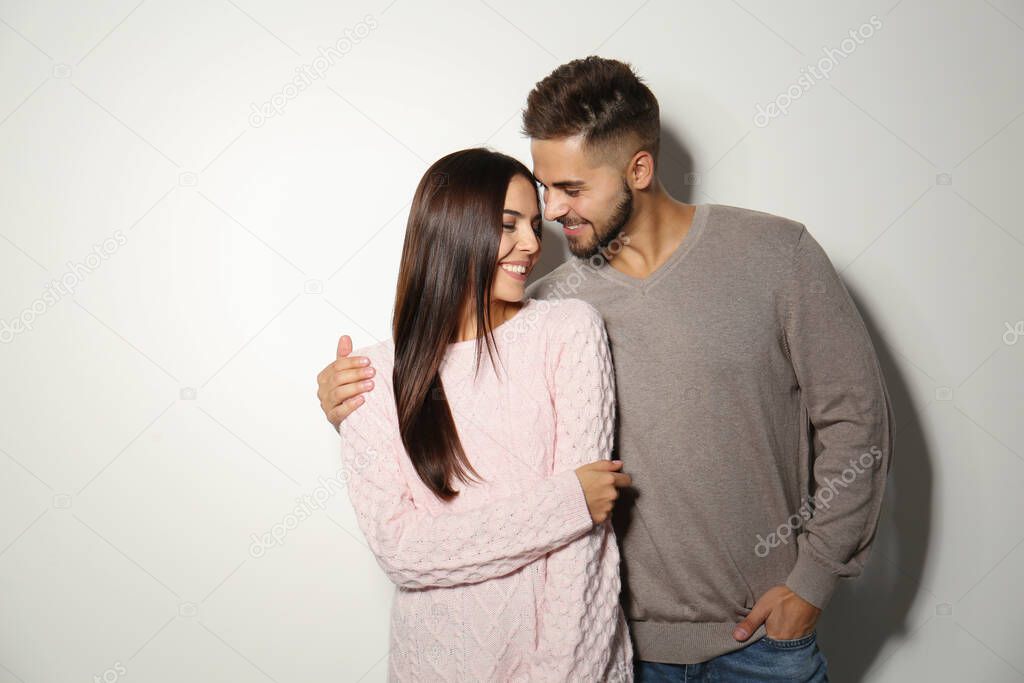 Lovely couple in warm sweaters on light background 