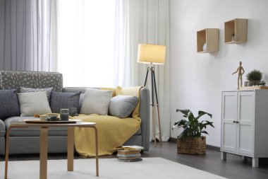 Pencerenin yanında rahat kanepesi olan şık bir oturma odası. İç tasarım