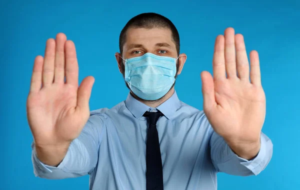 Hombre Con Máscara Protectora Mostrando Gesto Stop Sobre Fondo Azul — Foto de Stock