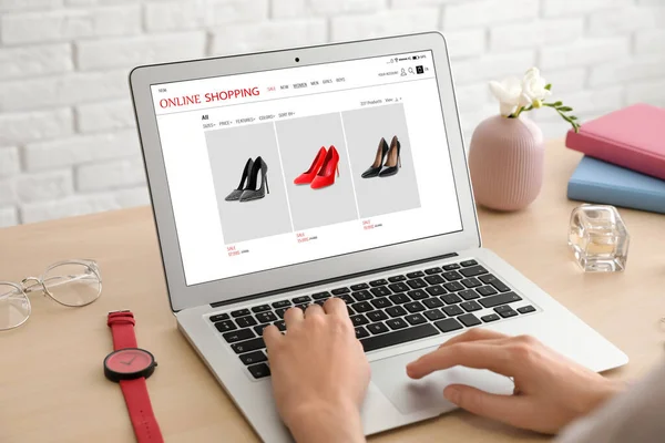 İnternetten alışveriş yapan kadın masadaki dizüstü bilgisayarını kullanıyor, yakın plan.