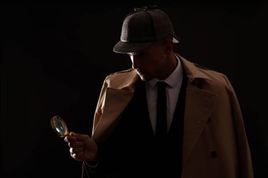 Siyah arka planda büyüteç olan eski moda dedektif.