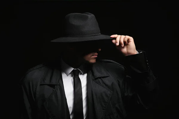 Old fashioned detective in hat on dark background