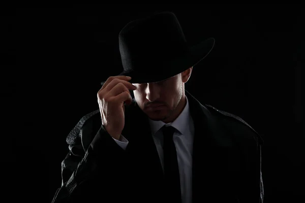 Old fashioned detective in hat on dark background