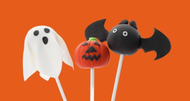 Turuncu arka planda Cadılar Bayramı temalı pastalar.