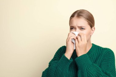 Hafif arka planda hapşıran genç bir kadın, mesaj için boşluk. Soğuk belirtileri