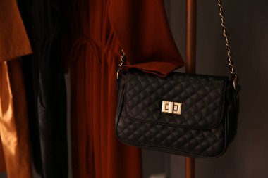 Butikte elbise askılığında şık bir kadın çantası.
