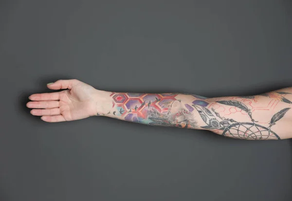 Donna Con Tatuaggi Colorati Sul Braccio Contro Sfondo Grigio Scuro — Foto Stock