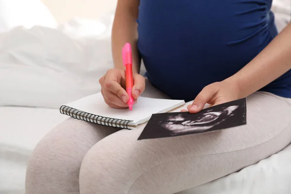 Schwangere Mit Notizbuch Und Sonogramm Namenswahl Für Baby Bett Nahaufnahme — Stockfoto