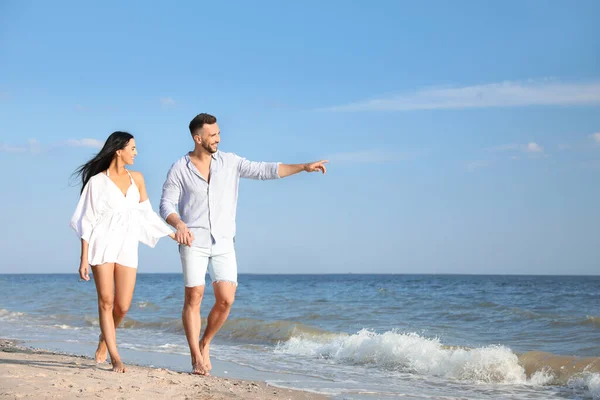 阳光明媚的日子 一对快乐的年轻夫妇在海滩散步 — 图库照片