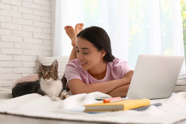 一个带着猫在靠窗的笔记本电脑上工作的年轻女人 总部概念 — 图库照片