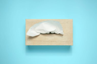 Açık mavi arka planda kağıt mendilli ahşap tutucu, üst görünüm