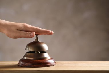 Ahşap masada otelin servis zilini çalan kadın, yakın plan. Metin için boşluk