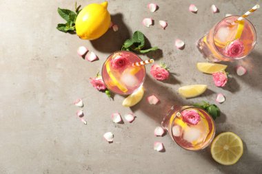 Gül çiçekleri ve açık gri masada limon dilimleri ile nefis ferahlatıcı bir içecek.