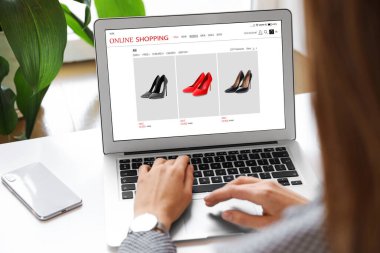 İnternetten alışveriş yapan kadın masadaki dizüstü bilgisayarını kullanıyor, yakın plan.