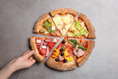 Gri masada nefis bir dilim pizza yiyen bir kadın.