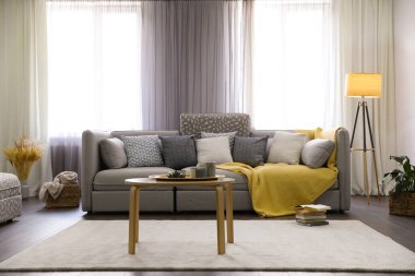 Pencerelerin yanında rahat kanepesi olan şık bir oturma odası. İç tasarım