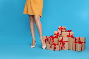 Açık mavi arka planda kadın ve hediye kutuları, yakın plan. Kara Cuma
