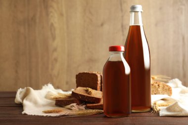 Lezzetli taze kvass şişeleri, çiviler ve ahşap masada ekmek.