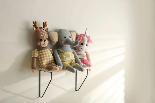 Shelf with cute toys on light wall. Baby room interior element