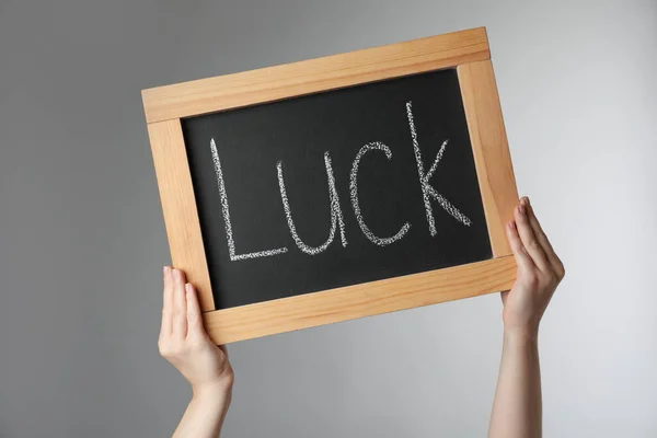 Mujer Sosteniendo Pizarra Con Palabra Luck Sobre Fondo Gris Claro — Foto de Stock