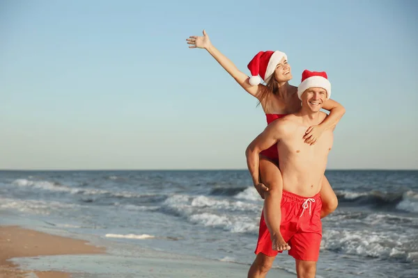 ビーチで一緒にサンタの帽子と幸せなカップル クリスマス休暇 — ストック写真