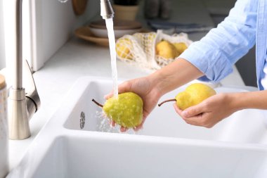 Mutfakta taze olgun armutları yıkayan kadın, yakın plan.