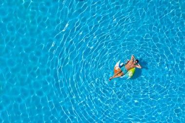 Yüzme havuzunda şişirilebilir yüzüklü genç bir adam. Metin için boşluk