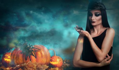 Geceleri sisli ormanda cadı kılığında, ürkütücü örümcekli genç bir kız. Cadılar Bayramı fantezisi