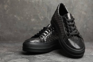 Gri taş masada bir çift şık siyah ayakkabı.