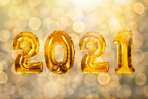 2021 yılbaşı kutlaması. Parlak altın balonlar ve arka planda bulanık ışıklar