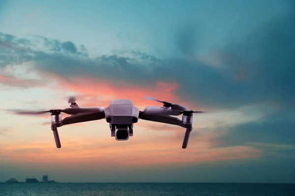 Modern drone flying over sea at sunset. Aerial survey