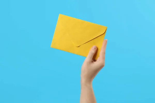 Mulher Segurando Envelope Papel Amarelo Fundo Azul Claro Close — Fotografia de Stock