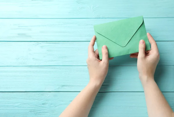 Vrouw Met Groene Papieren Envelop Aan Lichtblauwe Houten Tafel Bovenaanzicht — Stockfoto