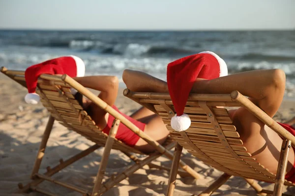 Piękna Para Kapeluszami Mikołaja Relaks Leżakach Plaży Święta Bożego Narodzenia — Zdjęcie stockowe