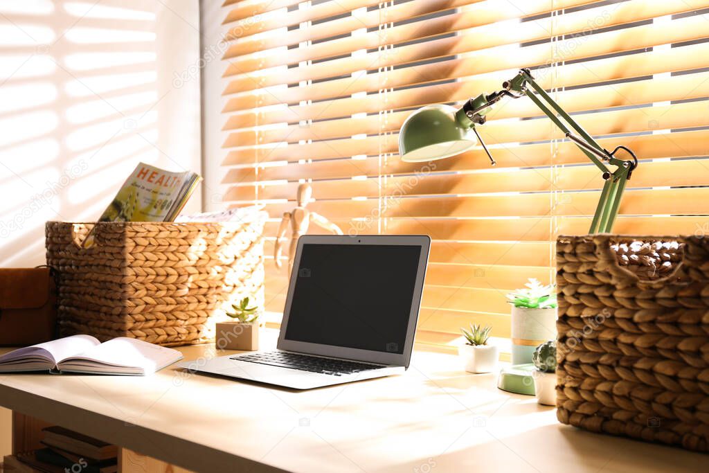 Comfortable workplace with laptop near window at home