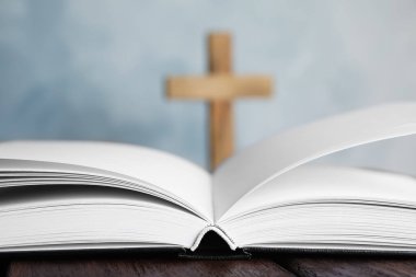 Masada İncil 'i aç ve arka planda bulanık haç, yakın plan. Hıristiyan dini