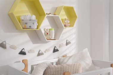 Çocuk odasındaki beyaz duvarda altıgen şekilli raflar. İç tasarım