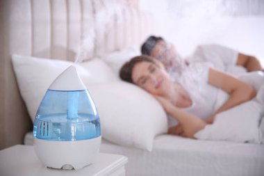 Çift yatak odasında modern hava nemlendiricisiyle uyuyor.