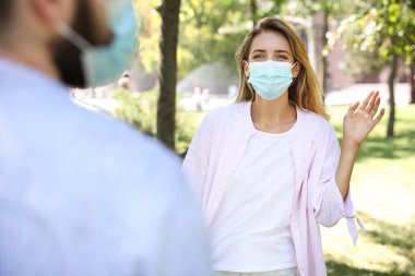 Dışarıdaki koruyucu maskeli kadın merhaba diyor. Koronavirüs salgını sırasında sosyal mesafeyi korumak