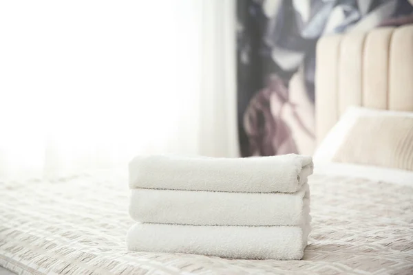 Clean white towels on bed at home
