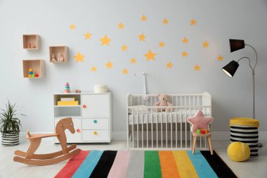 Bebek odasının içinde beşik ve oyuncaklar var.
