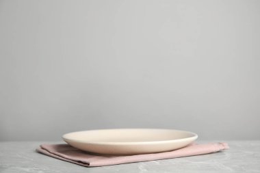 Açık gri mermer masada boş tabak ve pembe havlu. Metin için boşluk