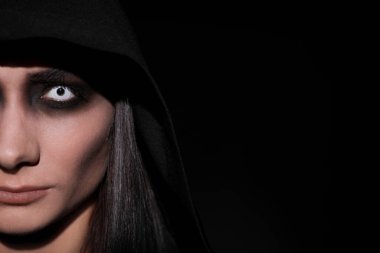 Siyah arka planda ürkütücü gözleri olan gizemli cadı, yakın plan. Metin için boşluk