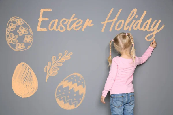 Kleines Mädchen Schreibt Osterfest Auf Graue Wand Mit Zeichnungen Schulferien — Stockfoto