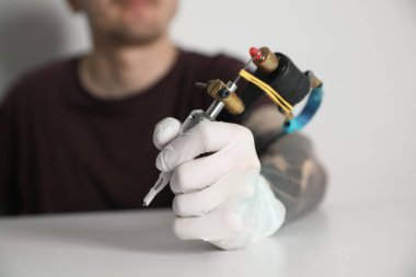 Masada ışık arkaplanına karşı profesyonel makineli dövme sanatçısı, yakın plan