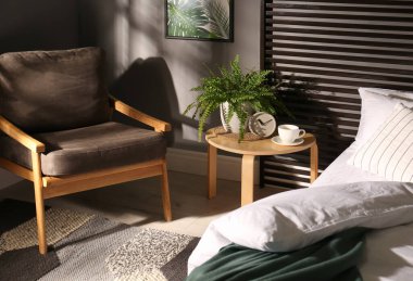 Koltuklu ve küçük masalı rahat bir yatak odası. İç tasarım