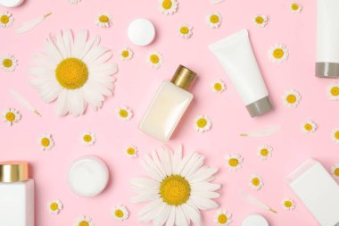 Pembe arka planda papatya ve kozmetik ürünleriyle düz kompozisyon