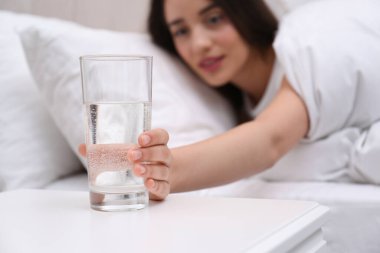 Evdeki komodinden bir bardak su alan genç kadın, eline odaklan.