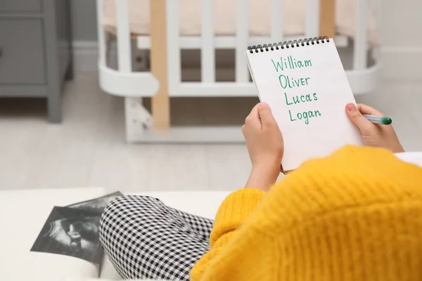 Pregnant woman with baby names list sitting on sofa, closeup